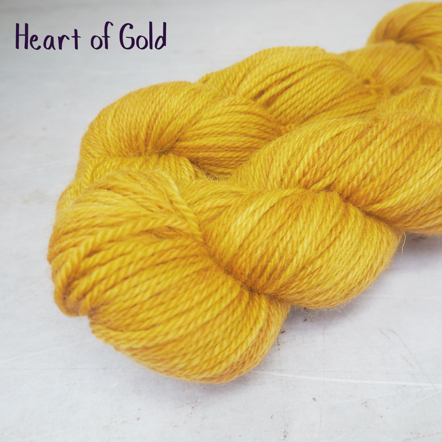 Two skeins of soft, DK-weight yarn, hand-dyed a rich golden yellow. 