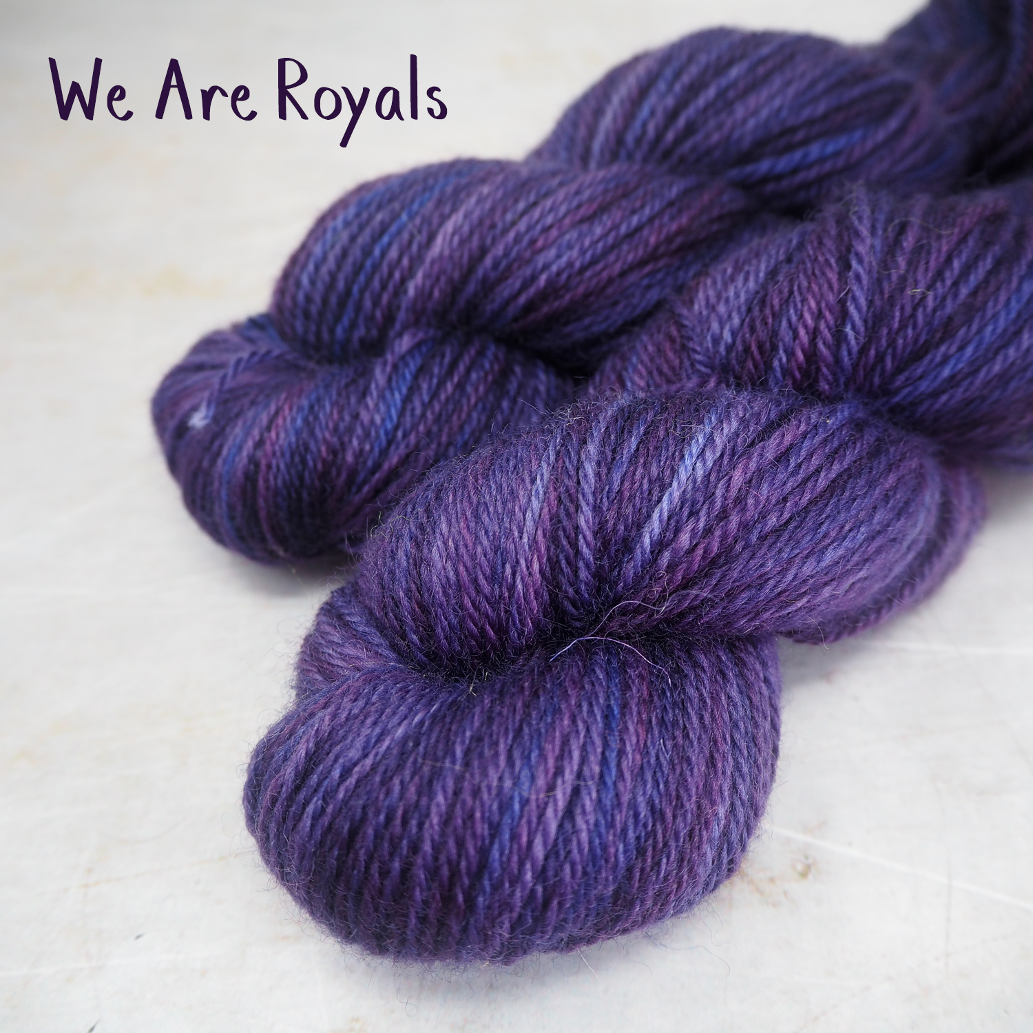 Two skeins of soft, DK-weight yarn, hand-dyed a in deep blues and purples. 
